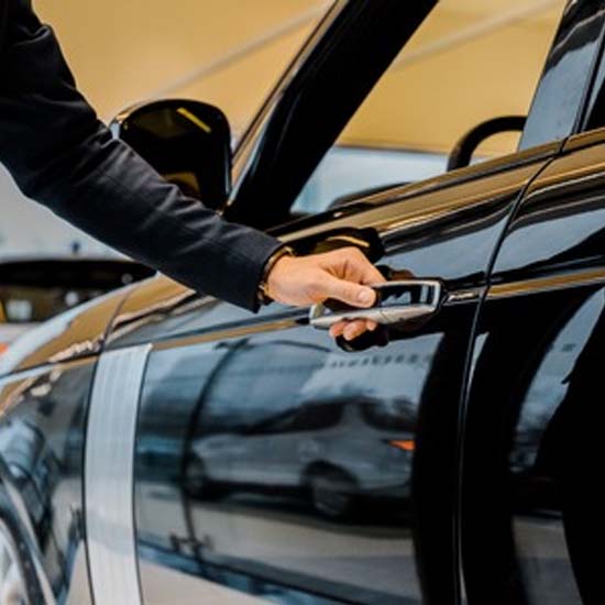 A chauffeur driver opening a door for his executive client
